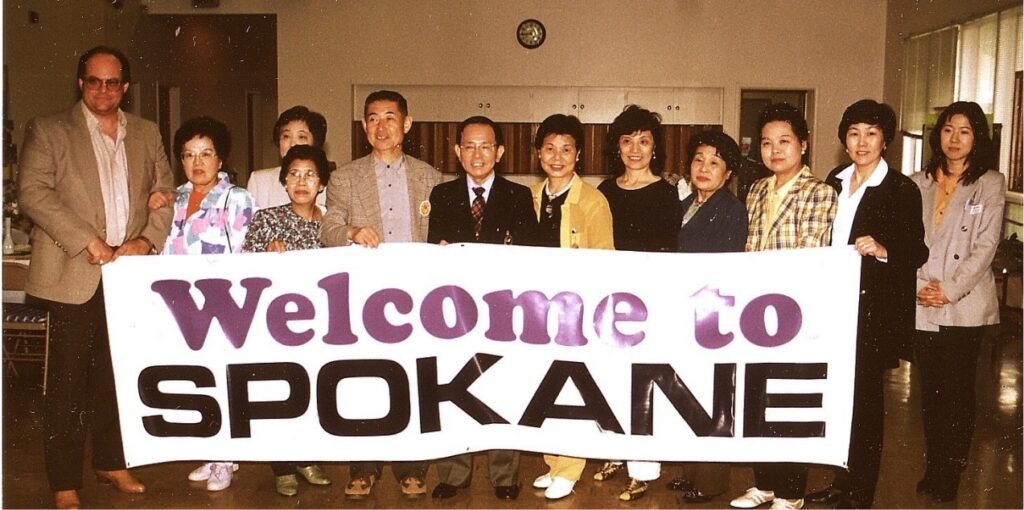 A group of exchange students with a sign saying 'welcome to Spokane'.