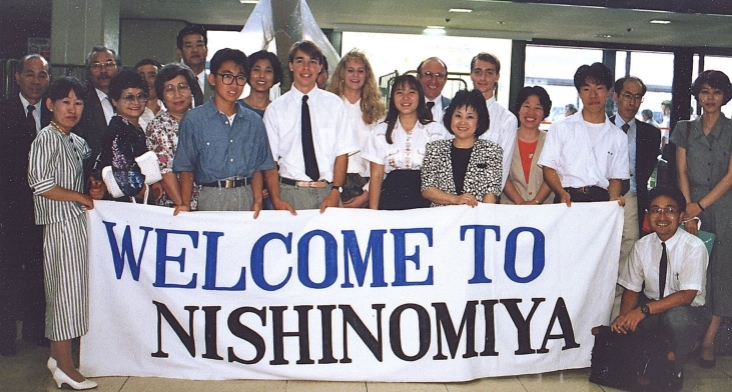 A group of exchange students with a sign saying 'welcome to Nishinomiya'.